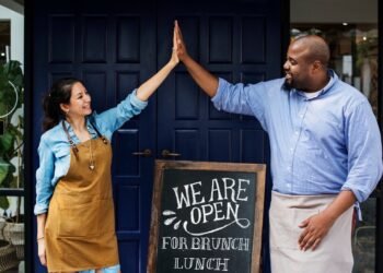 Cheerful business owners standing with open blackboard