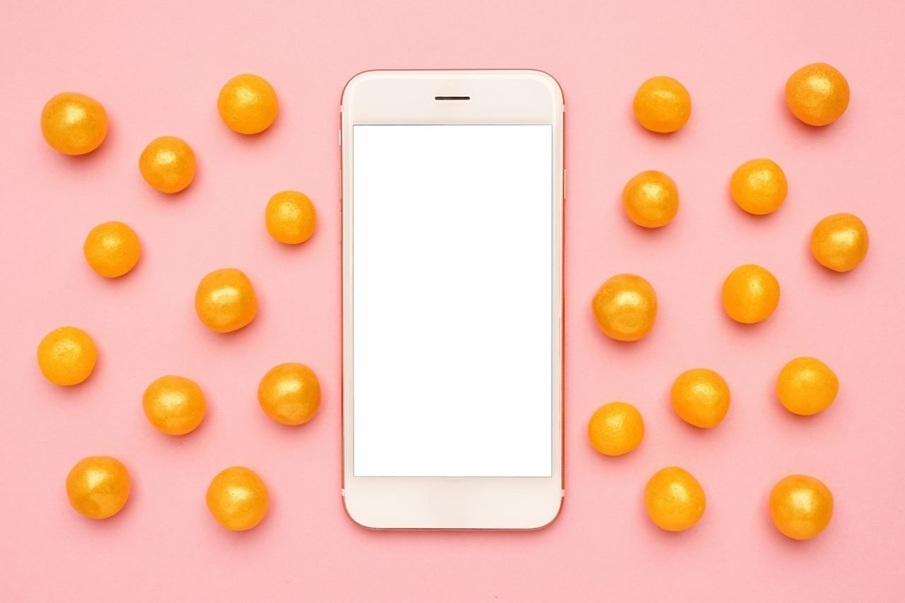Elementor #14798 mobile phone and sweet yellow candies on a pink background technology mock up